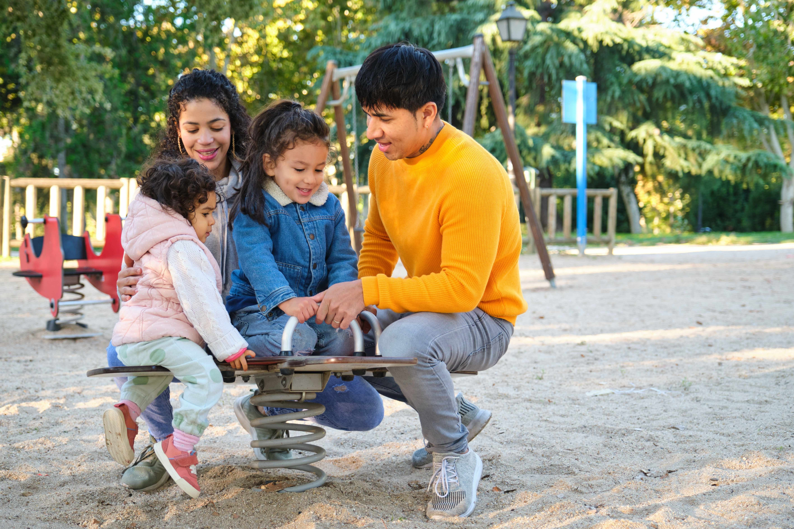Latin family of four playing at a playground